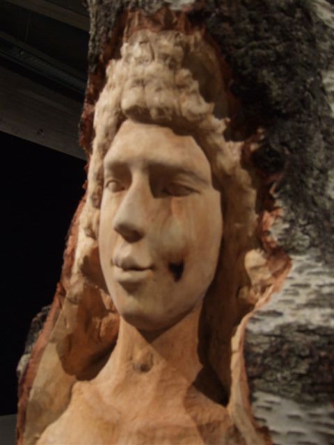 Close-up of a carved female figure in a tree trunk sculpture by Sanna Karlsson-Sutisna, from the Iroko exhibition at EMMA – Espoo Museum of Modern Art, 2010.