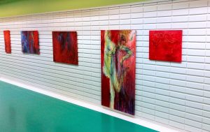 Encounter - Exhibition by Sanna Karlsson-Sutisna - Five abstract paintings in red and blue tones displayed on a white-tiled hospital corridor wall. - Jorvi hospital 2019.