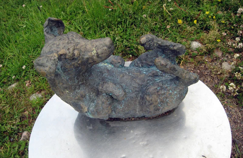 Public Artwork - Flower of Life - A bronze sculpture of a rounded animal lying on its back with its legs raised, displayed on a circular pedestal in a grassy park. - Art park, Pikku-Huopalahti, Helsinki, 2005.