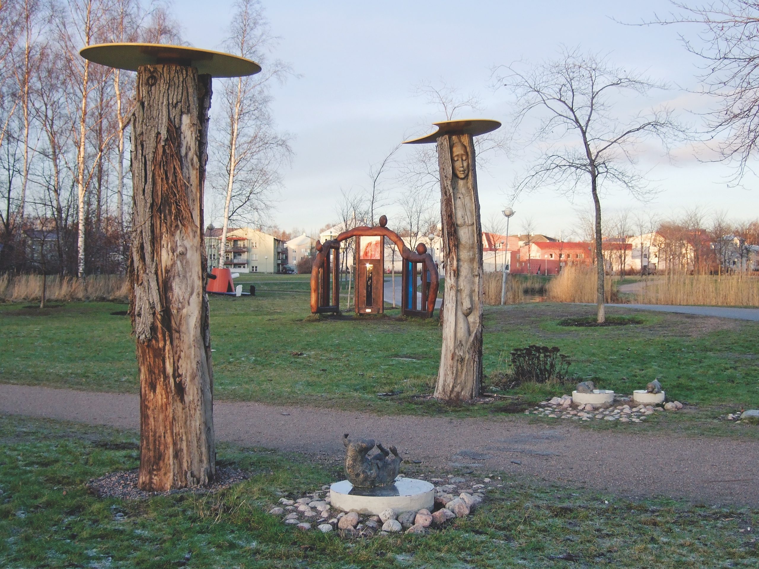 Public Artwork - Flower of Life - Wooden tree trunk sculptures and small bronze animal figures displayed in a grassy sculpture park. - Art park, Pikku-Huopalahti, Helsinki, 2005.