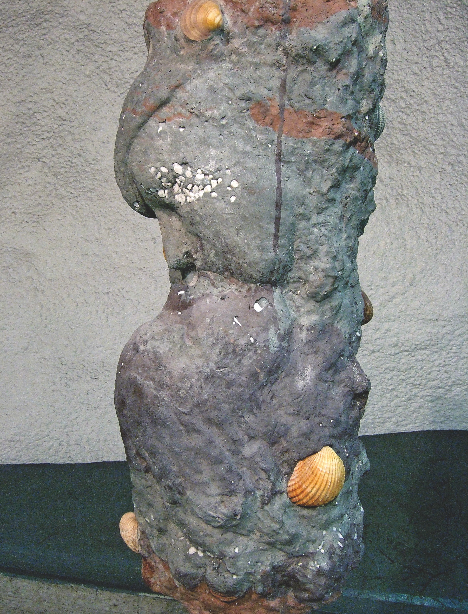 Public artwork Faces In The Metro concrete sculpture installation, close-up of a single sculpted face with embedded seashells at Helsinki Central Railway Metro station, 2007.