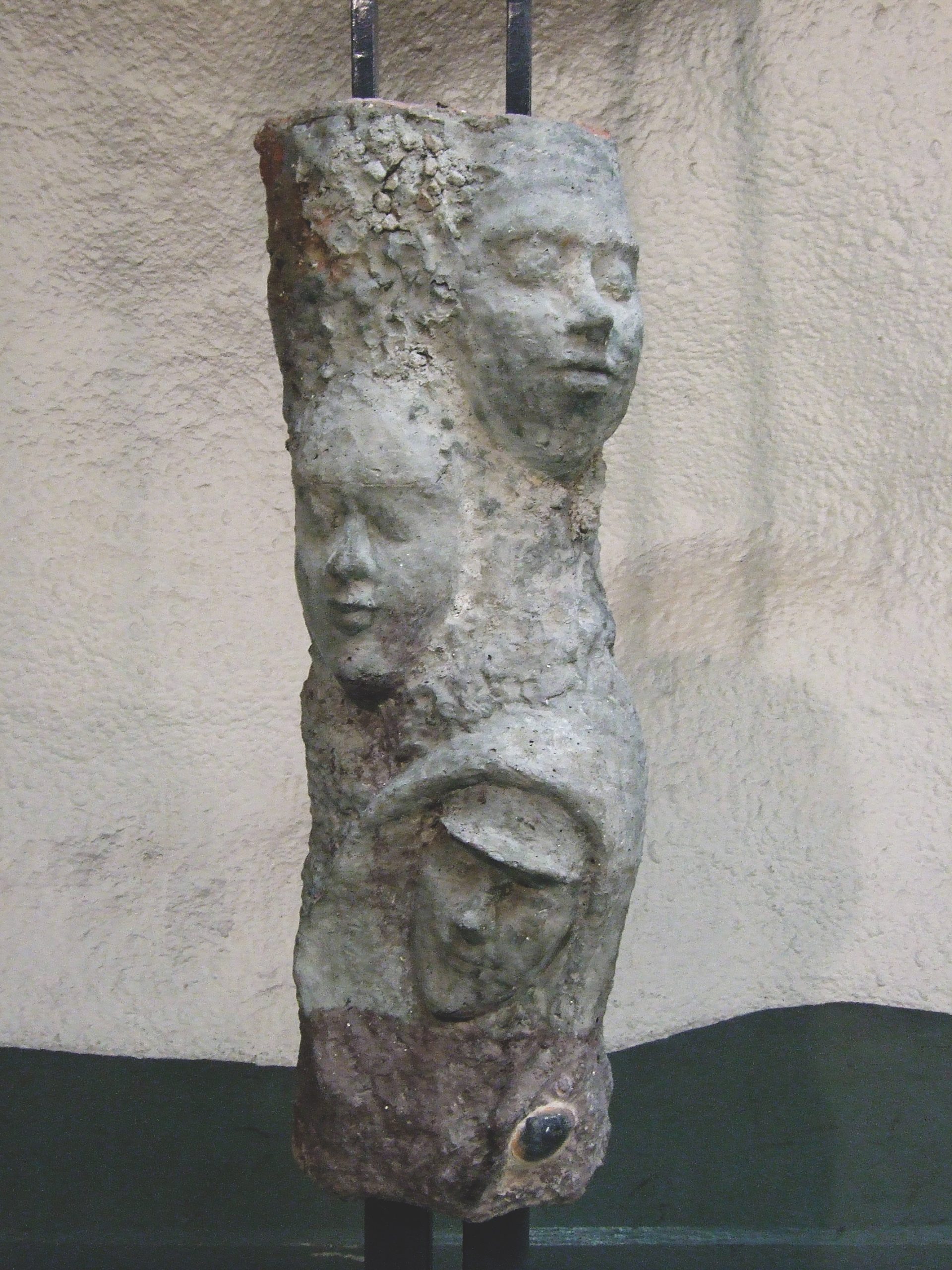 Public artwork Faces In The Metro concrete sculpture installation, full view of a concrete pillar featuring three sculpted faces at Helsinki Central Railway Metro station, 2007.