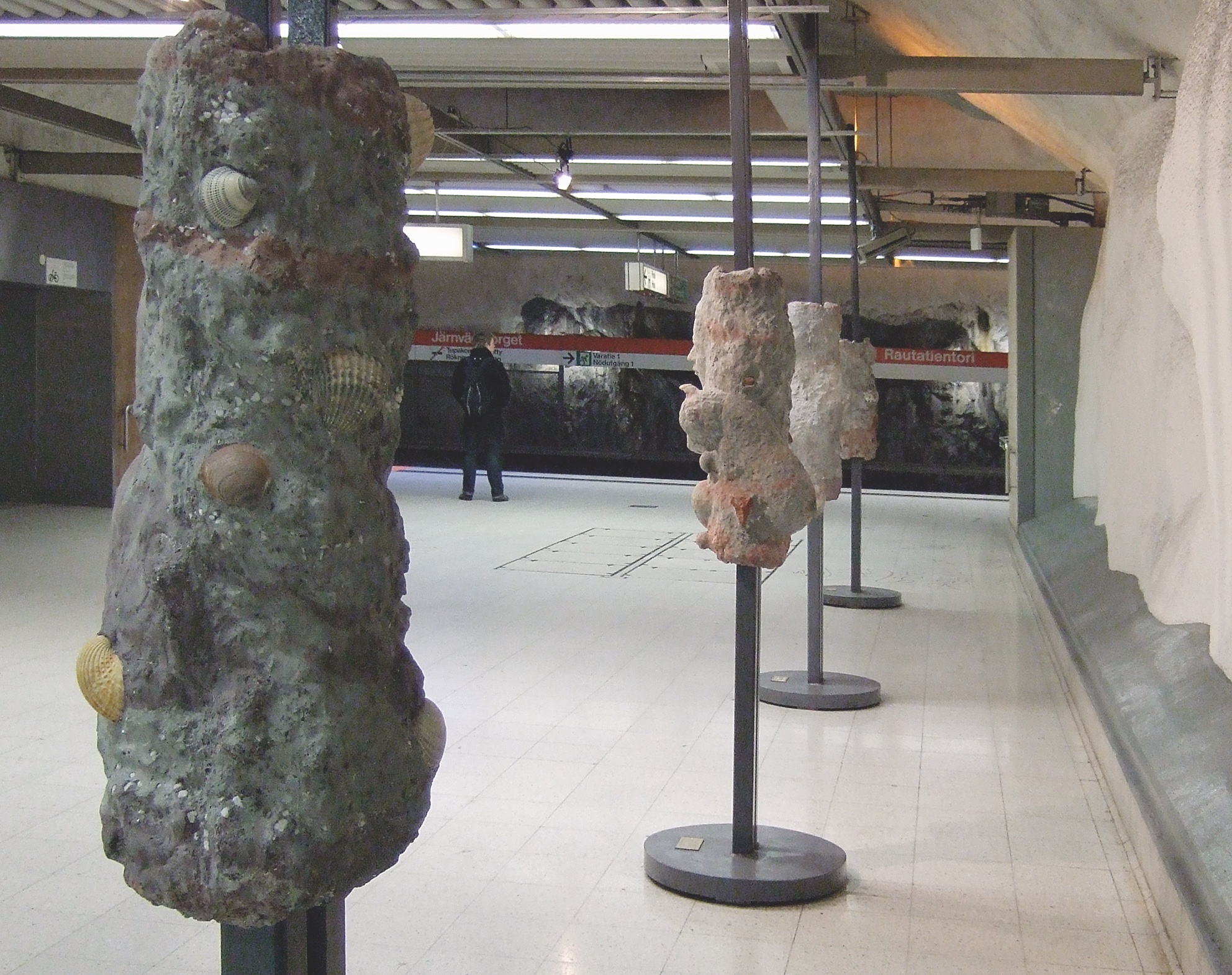 Public artwork Faces In The Metro concrete sculpture installation, side view of several sculpted faces at Helsinki Central Railway Metro station, 2007.